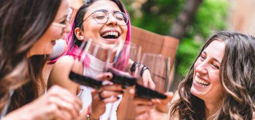 Freunde stoßen mit Rotweingläsern am Bartisch im Freien an