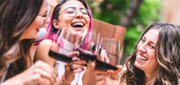 Freunde stoßen mit Rotweingläsern am Bartisch im Freien an