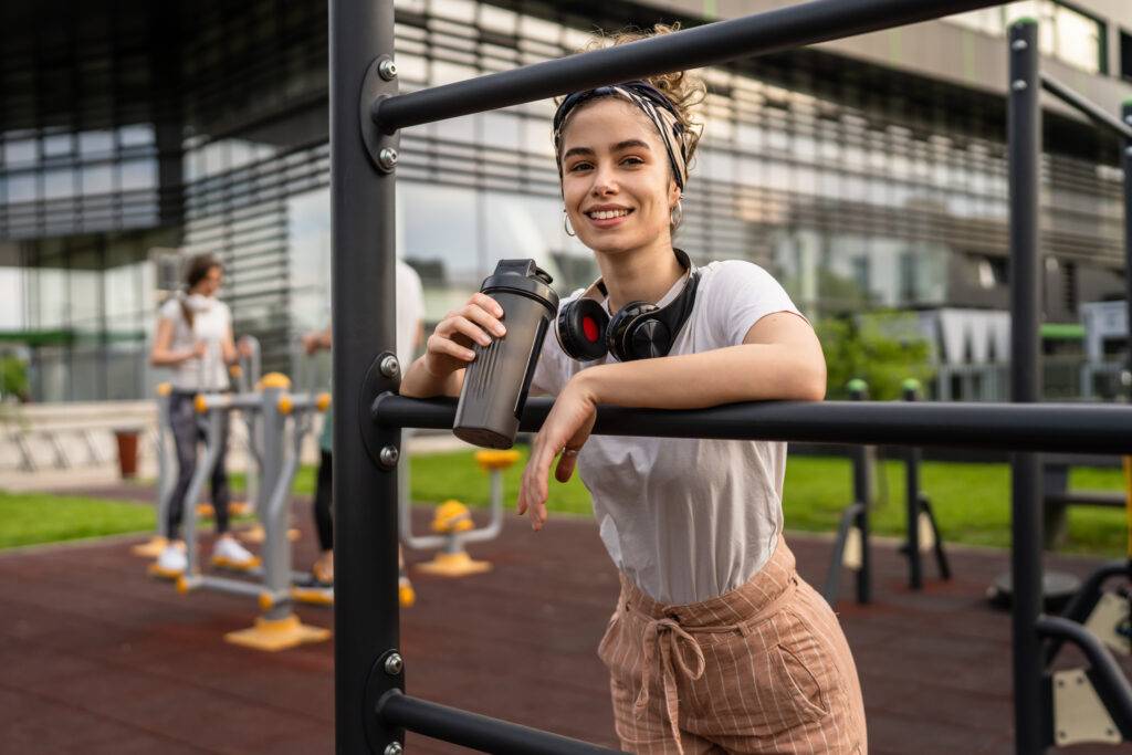 Eine Frau hält einen Shaker in der Hand und lächelt