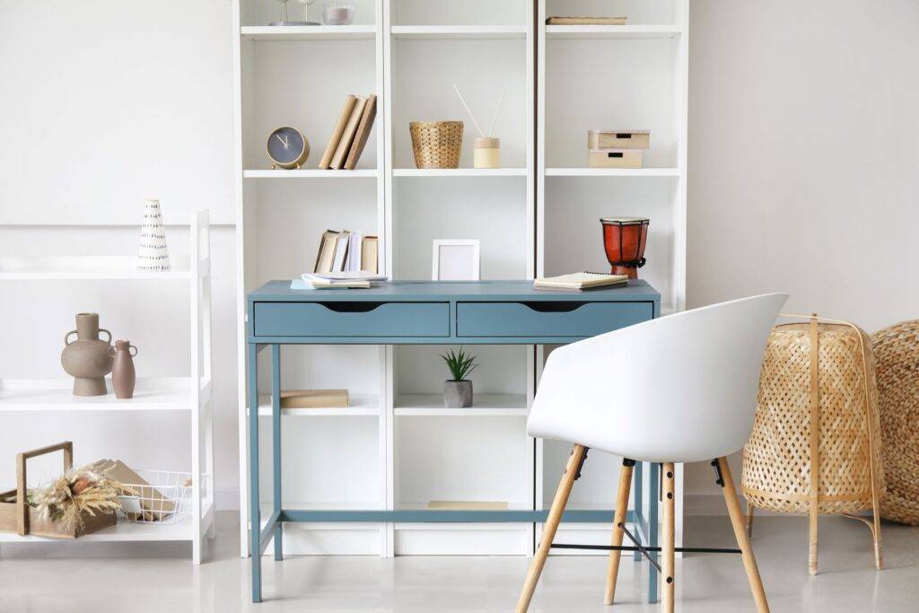 Blauer Schreibtisch neben hohem Bücherregal im Zimmer