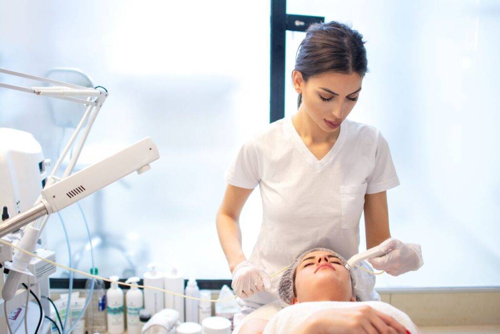 Kosmetikerin führt eine Hydrafacial Behandlung an einer Kundin durch, um die Haut tiefenwirksam zu reinigen und zu pflegen