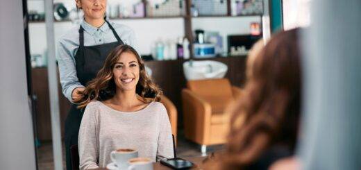 Spiegelreflexion einer glücklichen Frau und ihres Friseurs nach der Haarbehandlung im Salon.