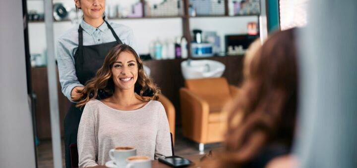 Spiegelreflexion einer glücklichen Frau und ihres Friseurs nach der Haarbehandlung im Salon.
