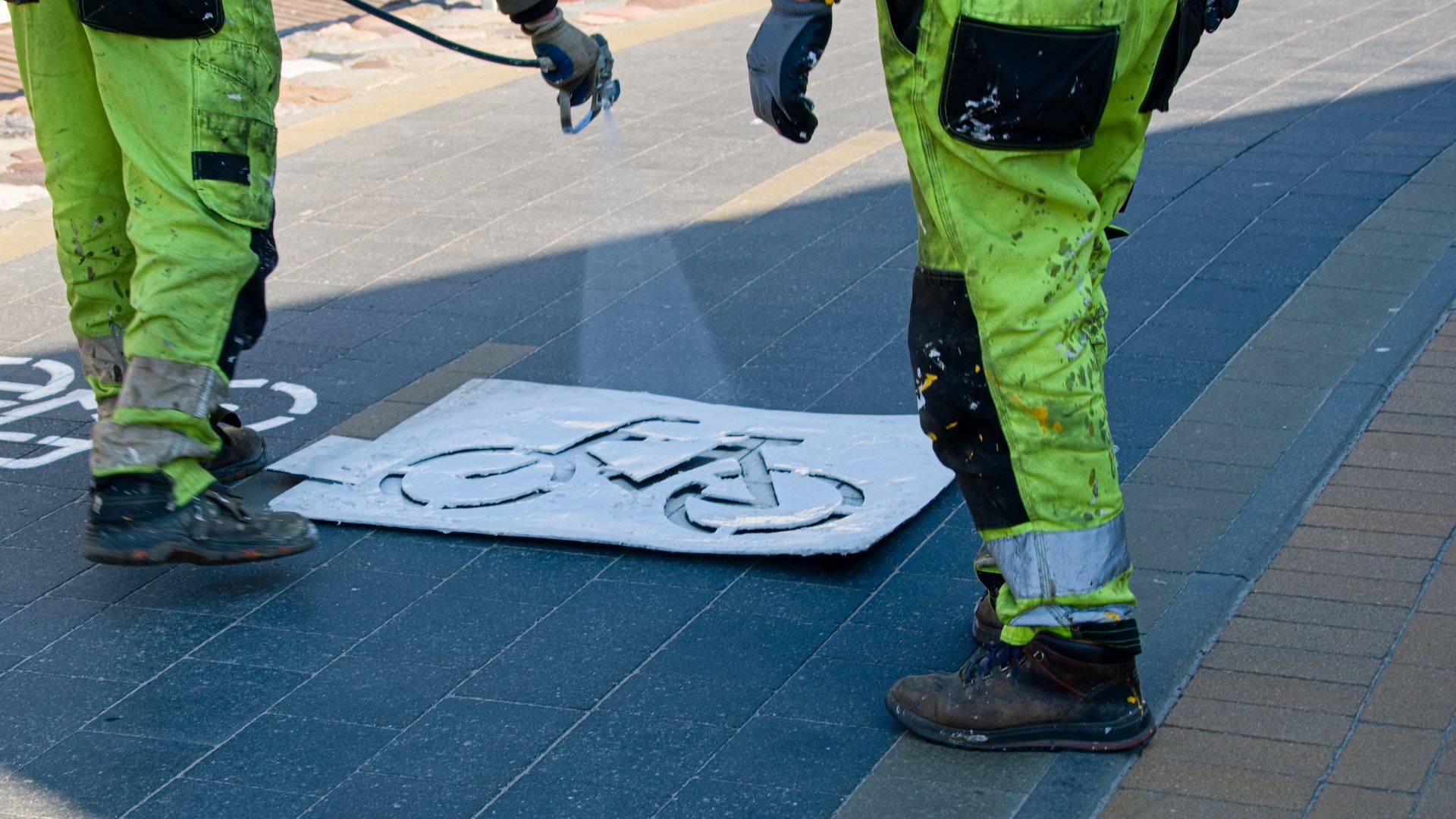 Arbeiter bringt Fahrrad-Bodenmarkierung auf