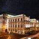 Beleuchtete Wiener Staatsoper bei Nacht mit Sternenhimmel – klassisches Wahrzeichen im naechtlichen Stadtbild