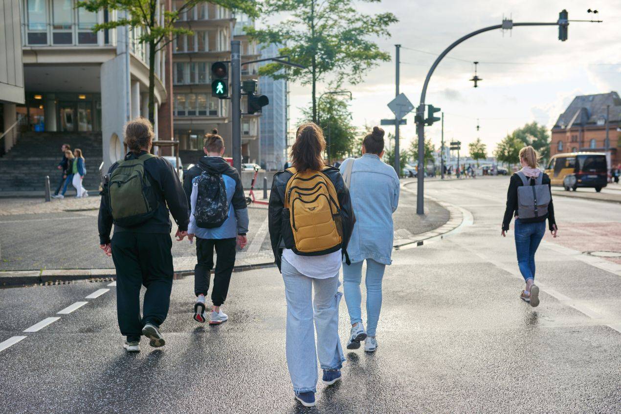 Gruppe von Jugendlichen ueberquert eine Hamburger Strasse auf Klassenfahrt bei sonnigem Wetter