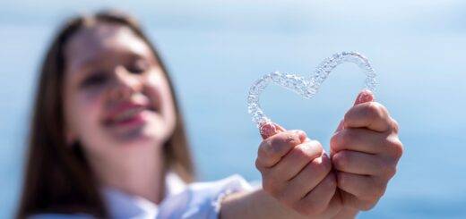 Maedchen haelt transparente Zahnschiene in Herzform vor sich – moderne Kieferorthopaedie Essen mit unsichtbarer Zahnspange