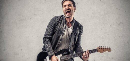 Gitarrist spielt energiegeladen vor grauer Wand | Akustikpaneel