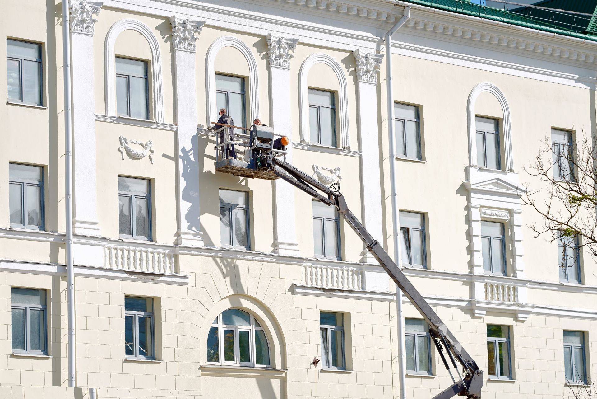 Zwei Männer auf Lkw-Arbeitsbühne vor Gebäudefassade
