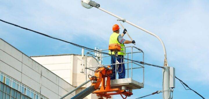 Arbeiter auf Lkw-Arbeitsbühne unter blauem Himmel