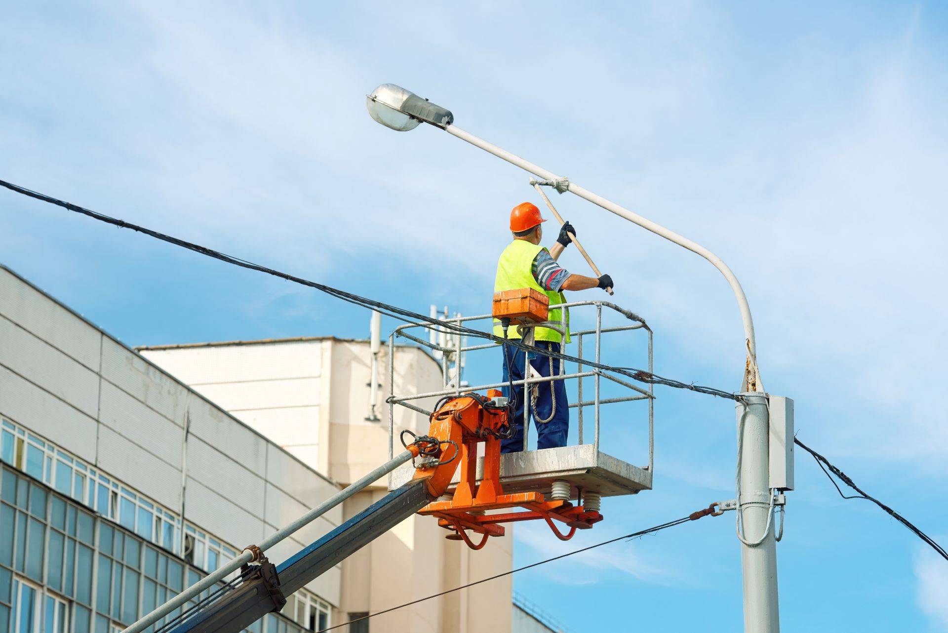 Arbeiter auf Lkw-Arbeitsbühne unter blauem Himmel